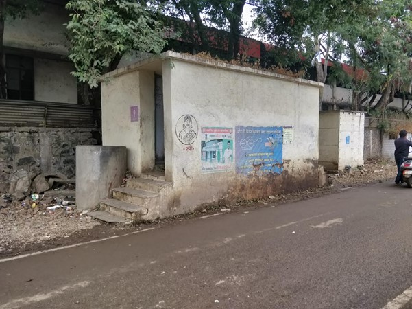 This photo shows a concrete structure with four steps leading to an open entryway on the side of a street, which is the only community toilet opposite the houses of Sex Workers in Sangli, Maharasthra, where roughly 250 people live